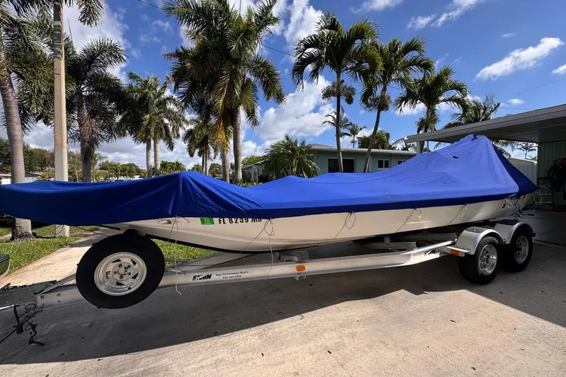 Slide: The Image of 2005 Storm Boats Storm-High Performance boat on trailer, covered with blue tarp, palm trees in background. - 61