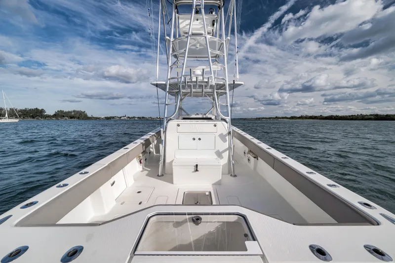 Slide: The Image of 2021 SeaVee 390Z boat on water, featuring spacious deck and tower under cloudy sky. - 12