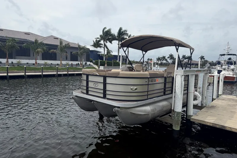 Slide: The Image of 2020 Veranda Relax VR 22 RC pontoon boat docked by waterfront homes. - 2