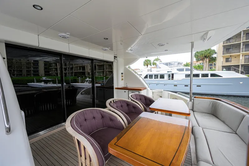 Slide: The Image of Luxurious 2013 Hatteras 80 Motor Yacht deck with elegant seating and wooden tables. - 2