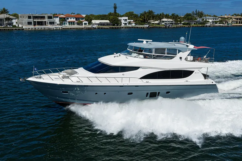 Slide: The Image of 2013 Hatteras 80 Motor Yacht cruising on blue water near coastal homes. - 80