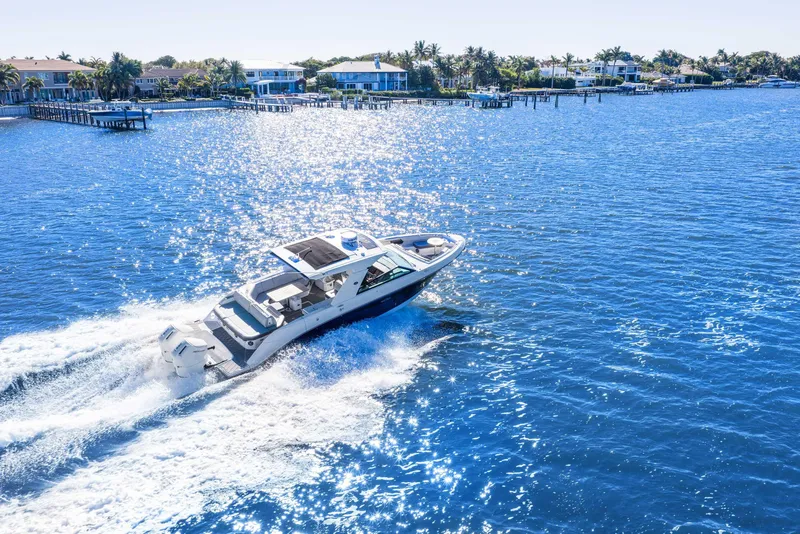 Slide: The Image of 2023 Sea Ray SLX 400 Outboard cruising on a sunny, sparkling blue waterway. - 13