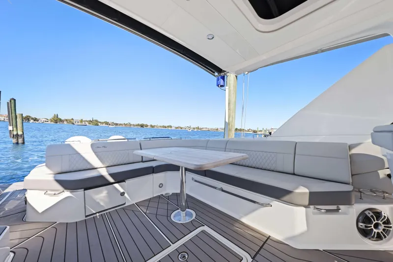 Slide: The Image of 2023 Sea Ray SLX 400 Outboard boat interior with elegant seating and table, overlooking serene waters. - 27