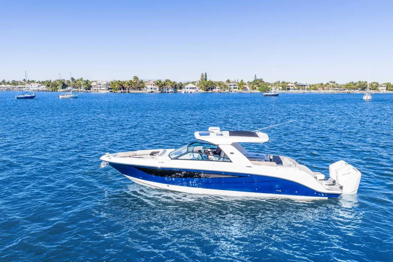 Slide: The Image of 2023 Sea Ray SLX 400 Outboard cruising on clear blue water near a coastal town. - 47