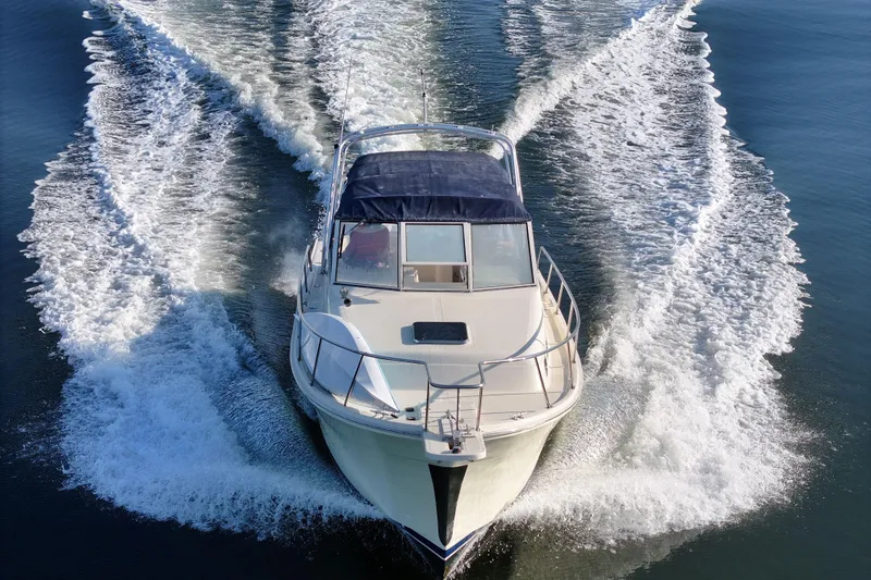 Slide: The Image of 2004 Mainship Pilot 30 Rum Runner cruising on open water, creating a dynamic wake. - 16