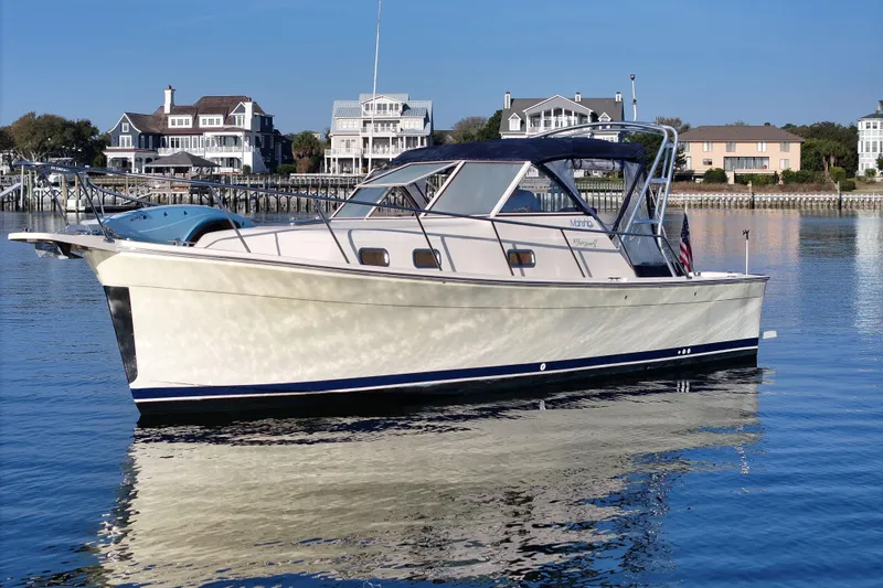 Slide: The Image of 2004 Mainship Pilot 30 Rum Runner boat on calm water near waterfront homes. - 2