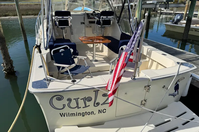 Slide: The Image of 2004 Mainship Pilot 30 Rum Runner boat docked, featuring seating and American flag. - 20