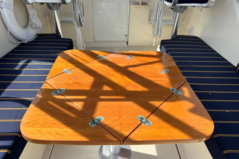 Slide: The Image of Wooden table on 2004 Mainship Pilot 30 Rum Runner boat with striped seating. - 23
