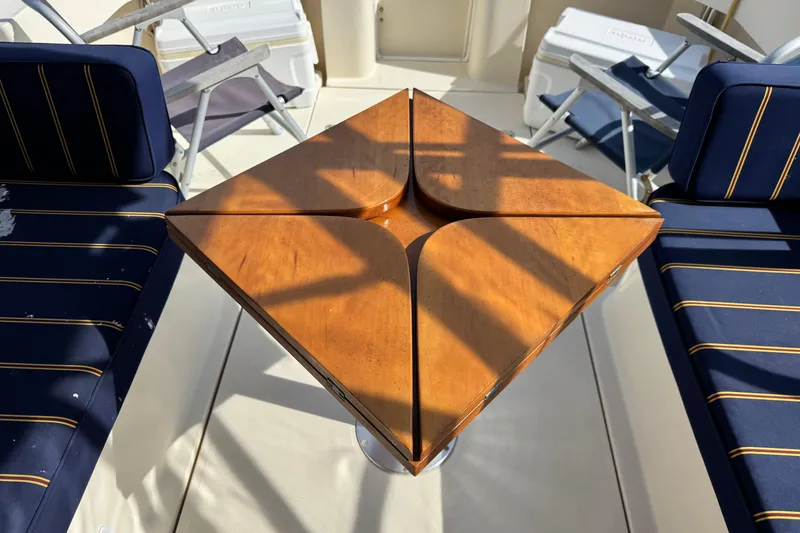 Slide: The Image of 2004 Mainship Pilot 30 Rum Runner interior with wooden table and navy-striped seating. - 24