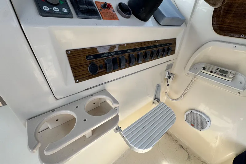 Slide: The Image of 2004 Mainship Pilot 30 Rum Runner control panel with switches, cup holders, and communication device. - 39