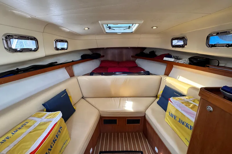 Slide: The Image of 2004 Mainship Pilot 30 Rum Runner cabin interior with seating, life jackets, and portholes. - 40