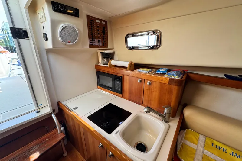 Slide: The Image of 2004 Mainship Pilot 30 Rum Runner galley with sink, stove, and microwave. - 47