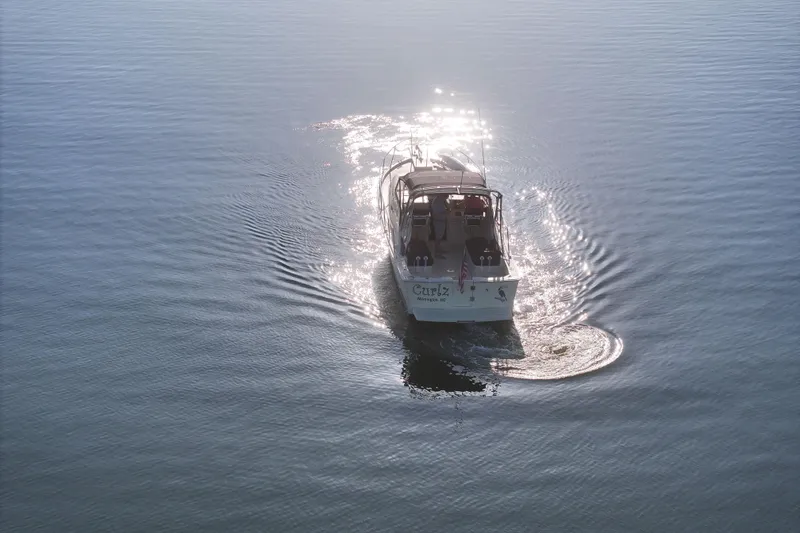 Slide: The Image of 2004 Mainship Pilot 30 Rum Runner cruising on calm water, sunlight reflecting beautifully. - 5