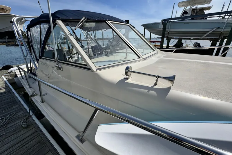 Slide: The Image of 2004 Mainship Pilot 30 Rum Runner docked, featuring sleek design and blue canopy. - 57