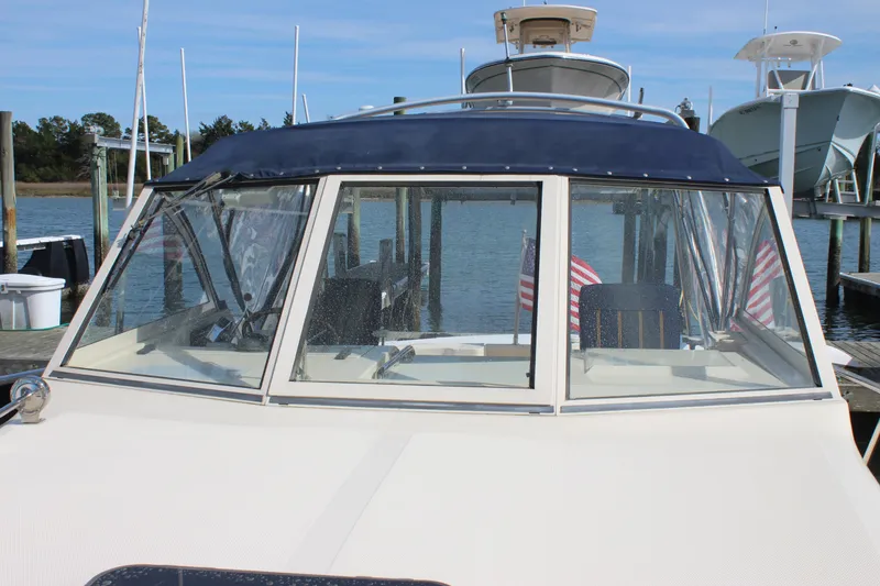 Slide: The Image of 2004 Mainship Pilot 30 Rum Runner docked, featuring a blue canopy and American flags. - 61