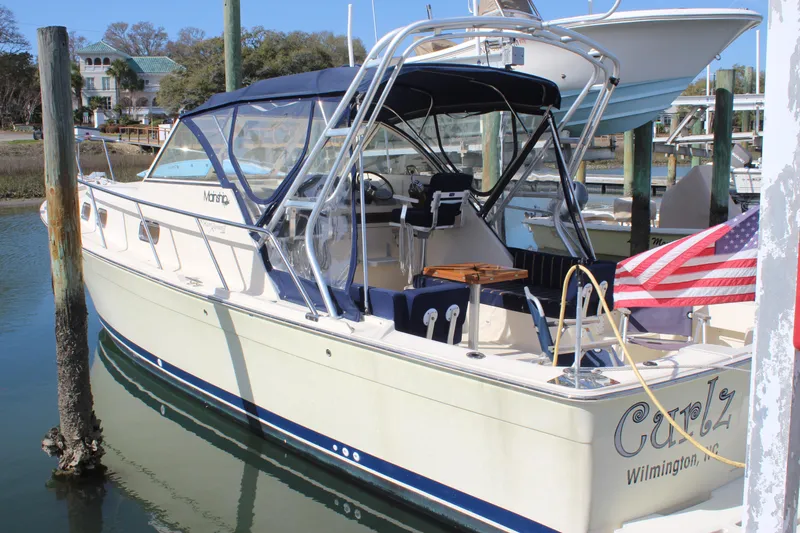 Slide: The Image of 2004 Mainship Pilot 30 Rum Runner docked, featuring a navy canopy and American flag. - 62
