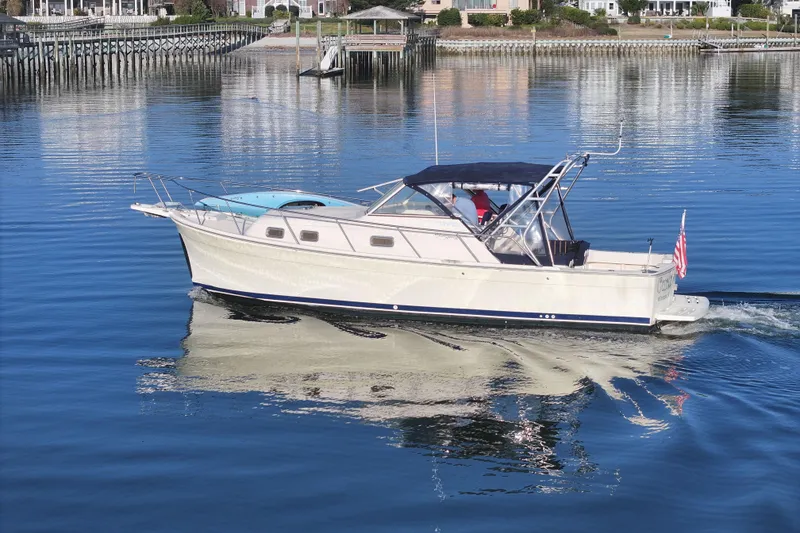 Slide: The Image of 2004 Mainship Pilot 30 Rum Runner cruising on calm waters near a dock. - 8