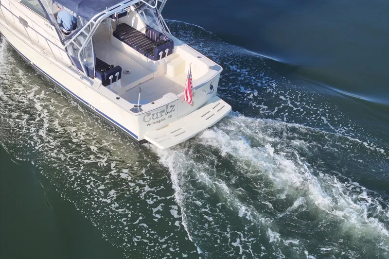 Slide: The Image of 2004 Mainship Pilot 30 Rum Runner cruising on calm waters, rear view. - 9