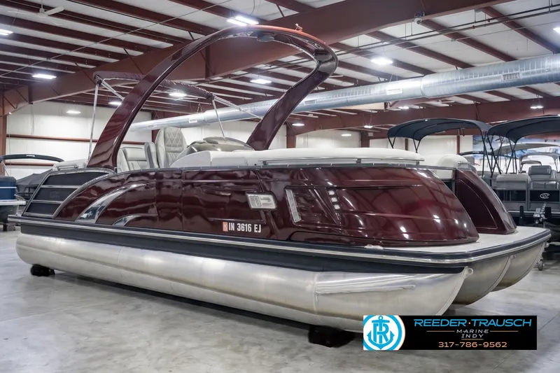 Slide: The Image of 2022 Bennington 23 QXFBA pontoon boat in showroom, featuring sleek maroon design. - 4