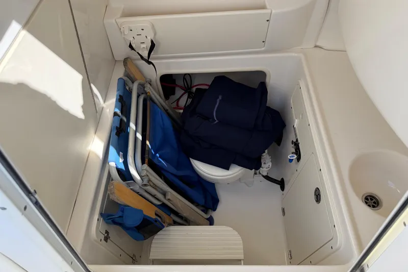 Slide: The Image of Storage area inside a 2004 Boston Whaler 270 Outrage, featuring folded chairs and equipment. - 12