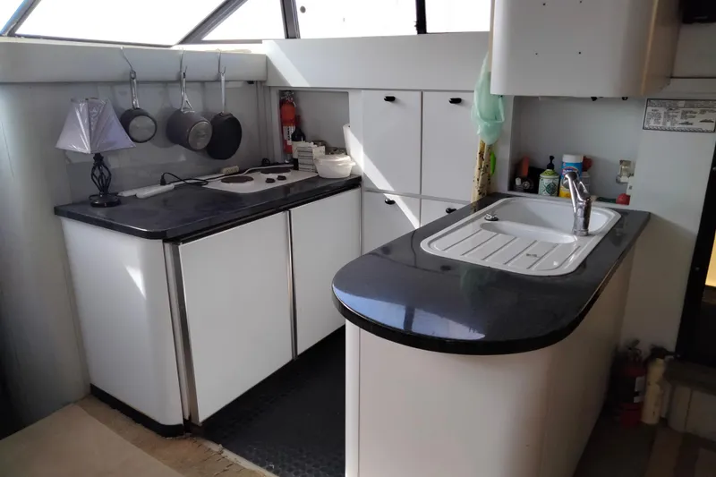 Slide: The Image of 1990 Mainship 41 Grand Salon yacht kitchen with modern countertops and hanging cookware. - 5