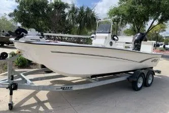 The Image of 2026 Mako Pro Skiff 19 CC boat on trailer, parked outdoors with trees in background. - 0