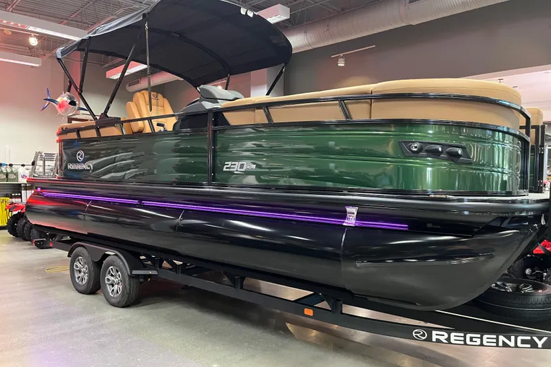 The Image of 2026 Regency 230 DL pontoon boat with green exterior on display indoors. - 0