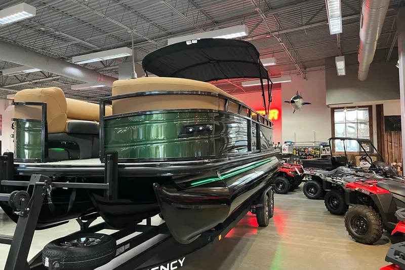 Slide: The Image of 2026 Regency 230 DL pontoon boat displayed indoors with ATVs nearby. - 2