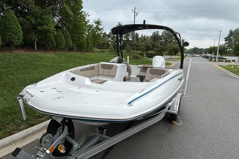 Slide: The Image of 2026 Tahoe 2150 boat on trailer, parked on a road near green grass and trees. - 4