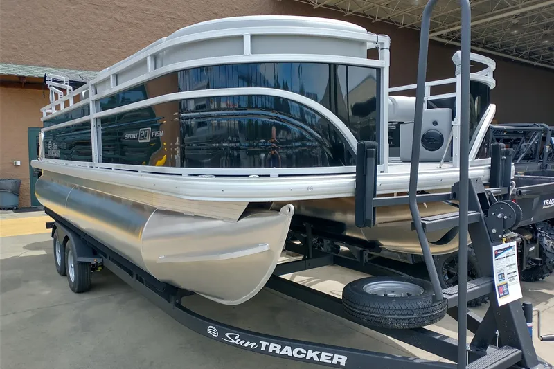 Slide: The Image of 2026 Sun Tracker SportFish 20 DLX pontoon boat on trailer, displayed outdoors. - 2