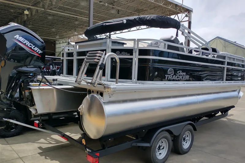 Slide: The Image of 2026 Sun Tracker SportFish 20 DLX pontoon boat with Mercury engine in a covered area. - 3
