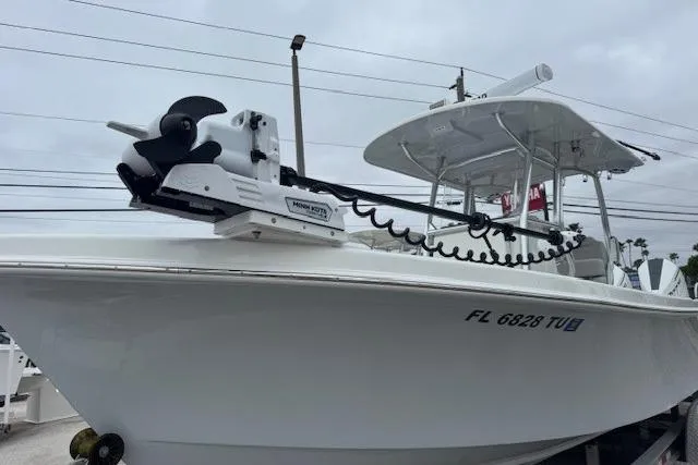 Slide: The Image of 2024 Pair Customs 27 Center Console boat with trolling motor, docked under cloudy skies. - 1