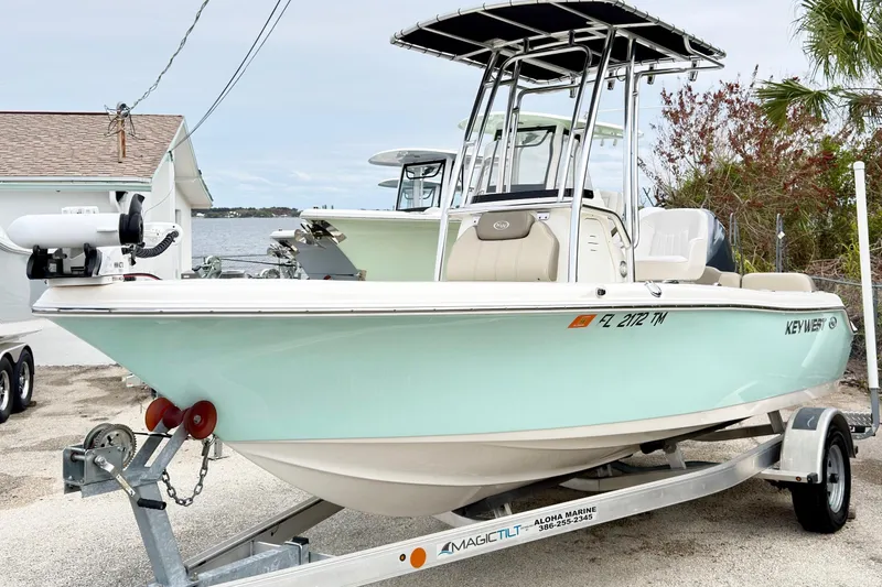 Slide: The Image of 2023 Key West 189 FS boat on trailer, light blue hull, parked near waterfront. - 3