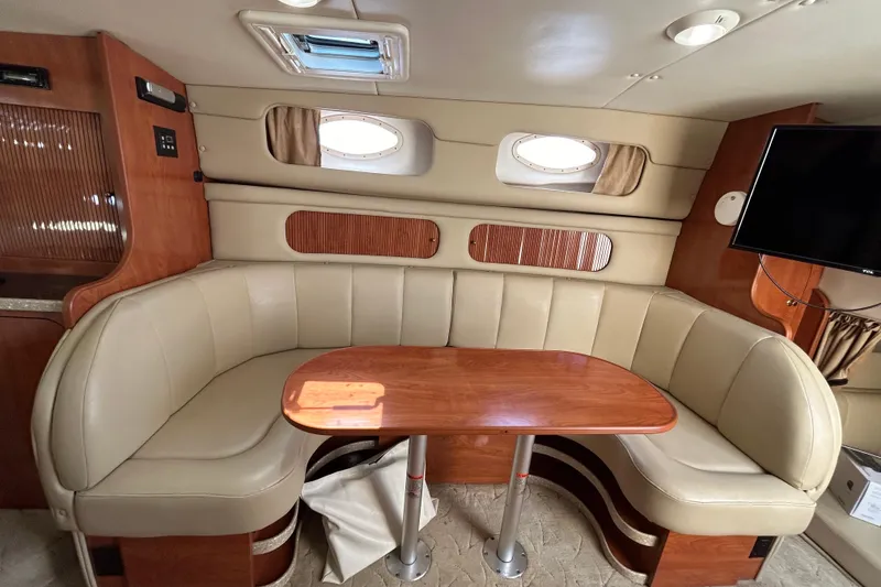 Slide: The Image of Interior of 2006 Rinker Fiesta Vee 342 with beige seating and wooden table. - 10