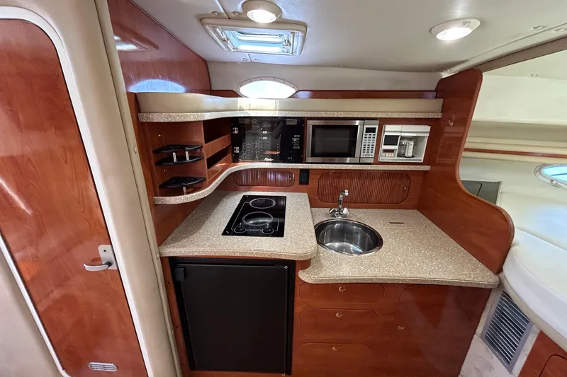 Slide: The Image of 2006 Rinker Fiesta Vee 342 boat kitchen with stove, sink, microwave, and wood cabinetry. - 9