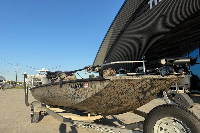 Slide: The Image of 2019 Xpress XP7 boat with camouflage design on a trailer, parked outside a building. - 5