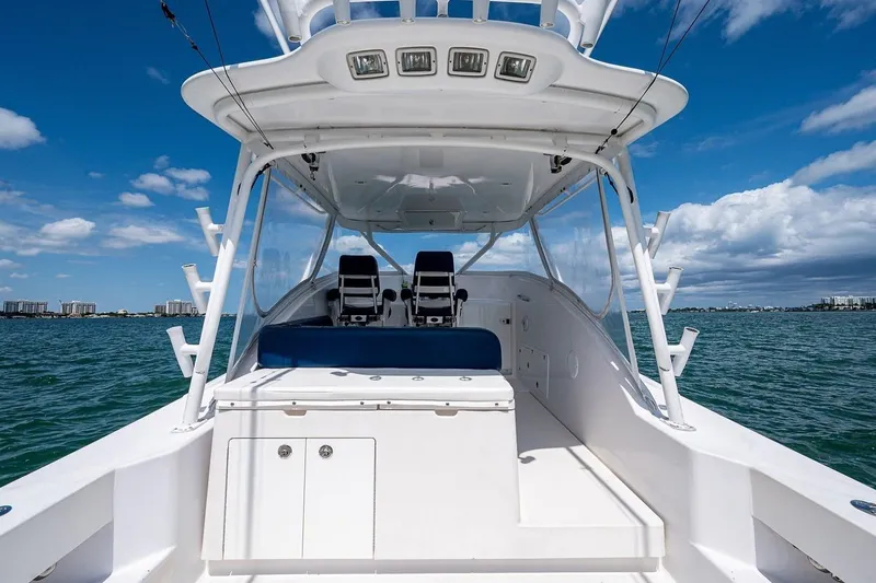 Slide: The Image of 2012 Brooks Boatworks 34 on water, featuring spacious deck and seating under clear blue sky. - 5