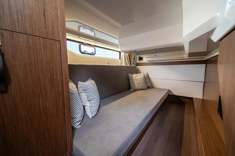 Slide: The Image of Manufacturer Provided Image: 2026 Beneteau Antares 12 Coupe interior with cozy seating and striped cushions. - 26