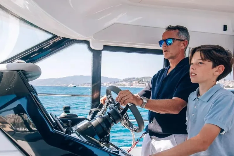 Slide: The Image of Man and boy steering Beneteau Antares 12 Coupe 2026 on the sea. - 5