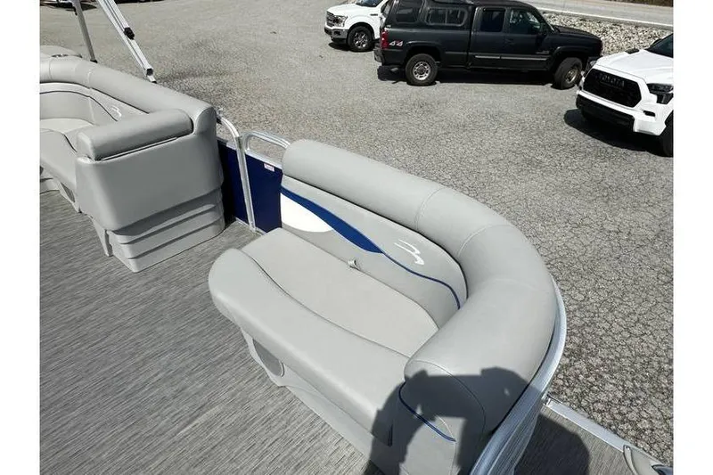 Slide: The Image of 2023 Bennington 20 SVL pontoon boat interior with gray seating, parked cars in background. - 13