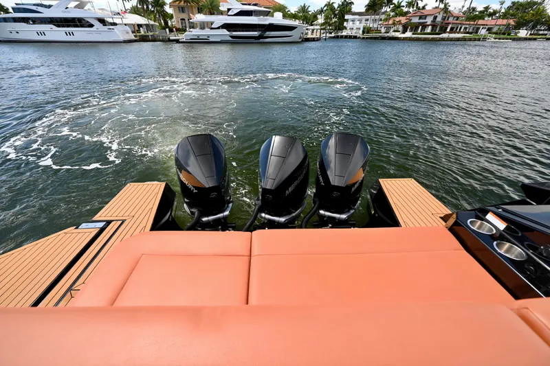 Slide: The Image of 2022 Cruisers Yachts 38 GLS OB with triple outboard engines on a serene waterfront. - 6
