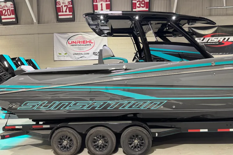 Slide: The Image of 2026 Sunsation 34 CCX boat in showroom, featuring sleek design and vibrant graphics. - 2