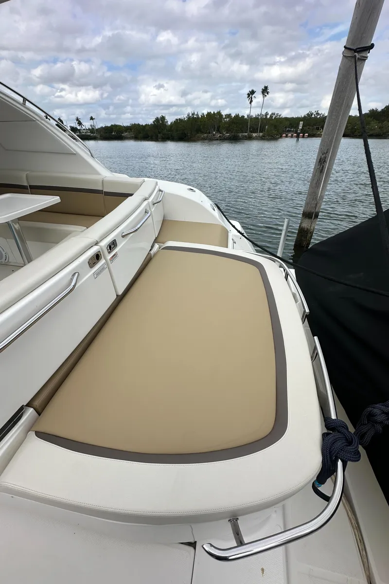 Slide: The Image of 2010 Sea Ray 470 Sundancer yacht with beige seating, docked by a scenic waterfront. - 17