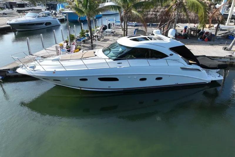 Slide: The Image of 2010 Sea Ray 470 Sundancer yacht docked in a marina with palm trees. - 2