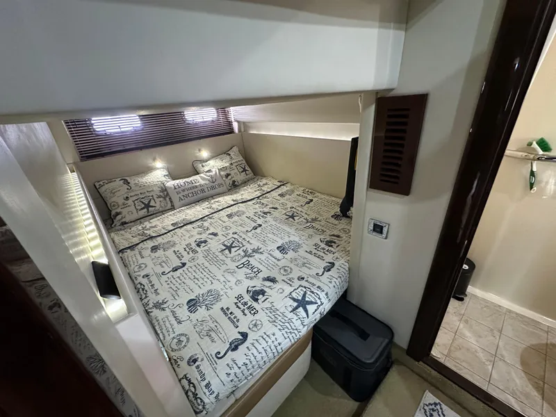 Slide: The Image of Cozy bedroom interior of 2010 Sea Ray 470 Sundancer yacht with nautical-themed bedding. - 29