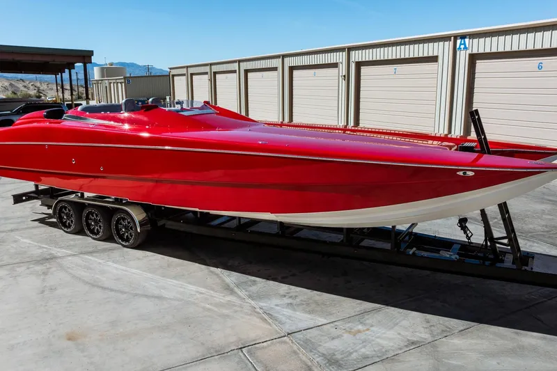 The Image of Red 2008 Nor-Tech 3600 Supercat boat on trailer, parked near storage units. - 0