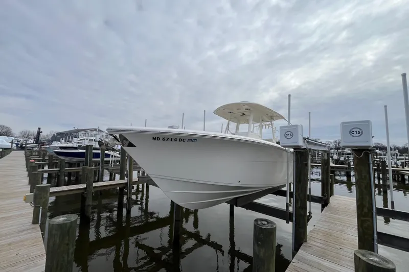 The Image of 2020 Cobia 301 Center Console boat docked at a marina under cloudy skies. - 0