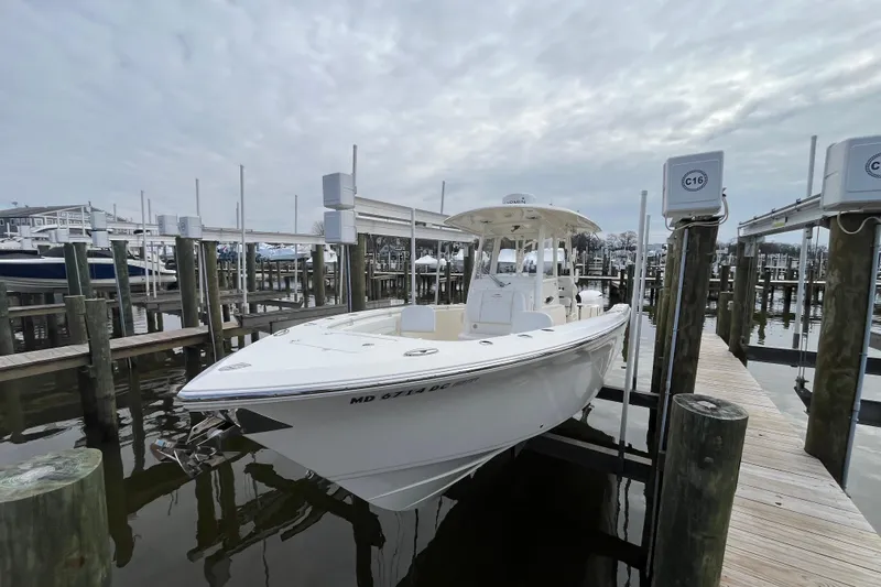 Slide: The Image of 2020 Cobia 301 Center Console boat docked at a marina under cloudy skies. - 2