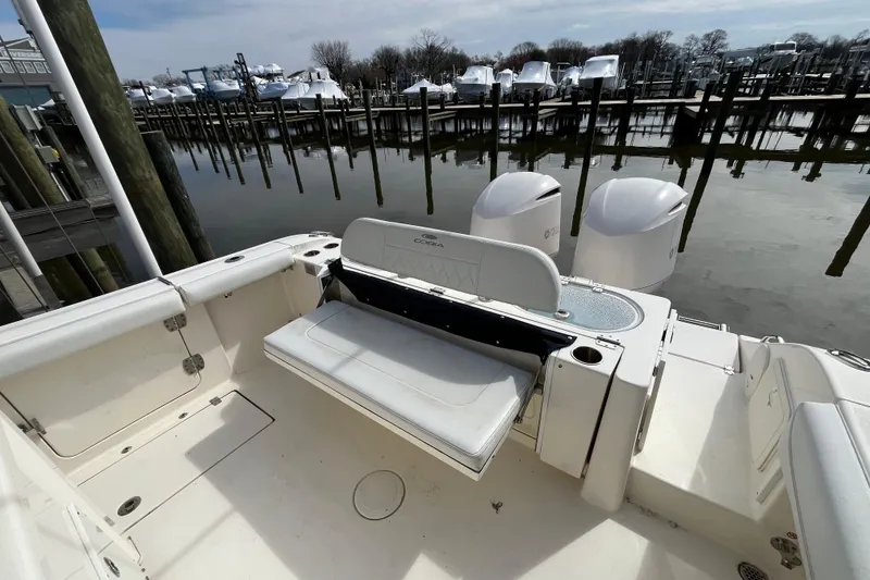 Slide: The Image of 2020 Cobia 301 Center Console boat at marina, featuring dual engines and seating area. - 8