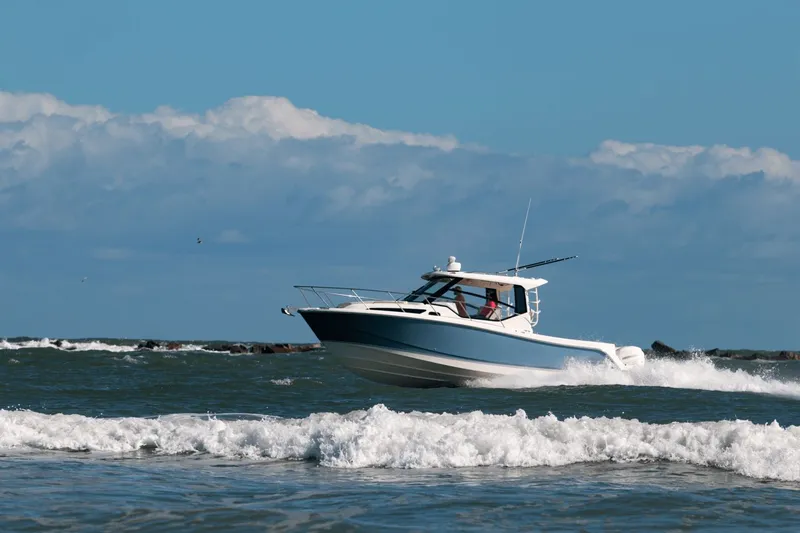 Slide: The Image of A 2027 Boston Whaler 325CQ speeds across the sea, surrounded by waves and a blue sky. - 40